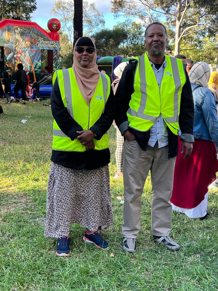 Two SWDA volunteers in high-visibility vests at a community family fun day in the park